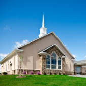 St Jacob's Lutheran Church is a beige building with a white steeple, arched windows, and stone accents. This charming church sits on a manicured green lawn under a clear blue sky.